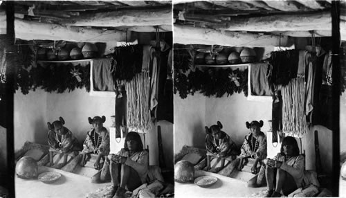 Hopi Indian Girls, showing peculiar method of hairdressing, grinding corn - Shonghopani, Arizona. [By Underwood 1905. PW 2/23/1984]