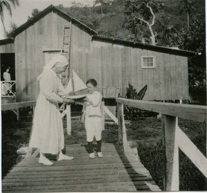 A deaconess together with a little boy, named Tamu, on the bridge leading to the Leper-house of Orofara