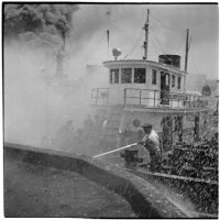Man fighting fires from a Navy Tugboat after the Markay oil tanker explosion in L.A. Harbor, Los Angeles, 1947