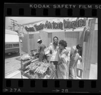Samuel Bassey serving barbecued chicken to Joan Murray at booth in Leimert Park in Los Angeles, Calif., 1984