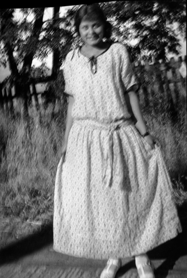 Young woman in dress standing next to fence