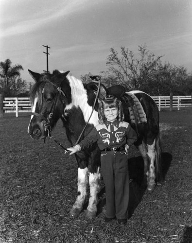 Little cowgirl poses with pony