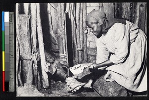 Woman feeding a pig, Uganda, ca.1920-1940