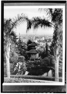 Exterior view of a two-story pagoda on a hill above the city below