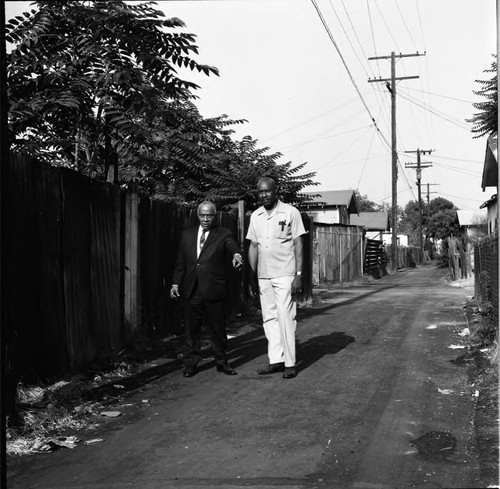 Gilbert Lindsay stands in a neighborhood alley with an unidentified man, Los Angeles
