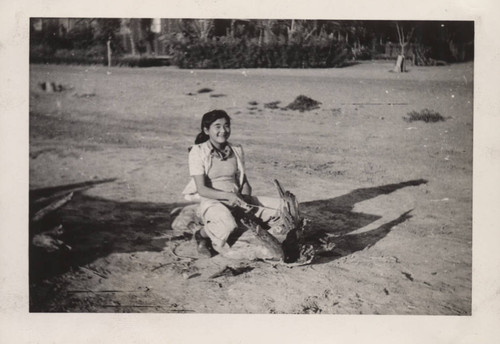 Girl sits on a log at Poston incarceration camp