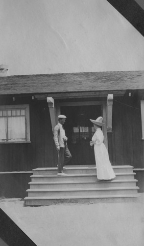 Man and woman on the steps of the Marine Biological Association of San Diego building at La Jolla Cove. The Association would became the Scripps Institution of Oceanography. Circa 1905