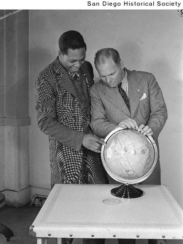 Boxer Archie Moore and his manager Jack Richardson looking at a globe