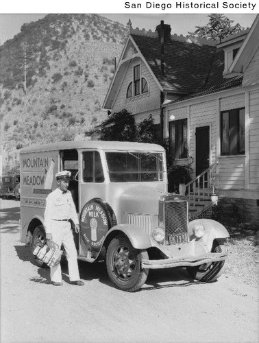 A Mountain Meadow Creameries milkman walking from his delivery truck to a home