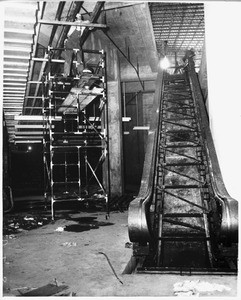 Workmen atop scaffold near escalator in under-construction Los Angeles Memorial Sports Arena, 1959
