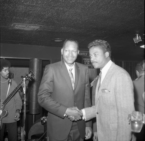 Tom Bradley shaking hands in a club during a campaign event, Los Angeles, 1969