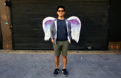 Unidentified man in shorts posing in front of a mural depicting angel wings
