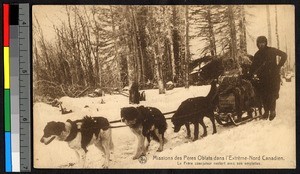 Missionary father with sled dog team amid a forest, Canada, ca.1920-1940