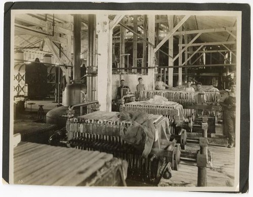 Men standing at the filter presses used for processing beet sugar, California
