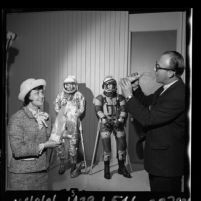 Frank J. Roberts, Apollo engineer demonstrating how astronauts eat to ARCS treasurer, Marion DeFore, Calif., 1965