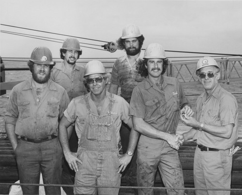 Global Marine, Inc. (GMI) rig floor team on the deck of the D/V Glomar Challenger (ship) during Leg 87 the Deep Sea Drilling Project. 1980