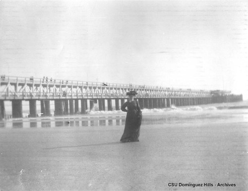 Woman at the beach next to a pier