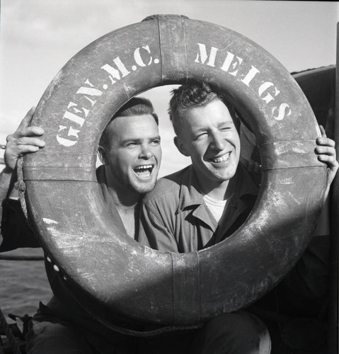 Two soldiers posing with USS Meigs life preserver