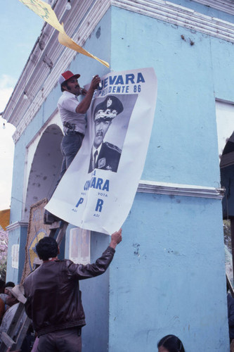 Two men hanging a campaign poster of presidential candidate Ángel Aníbal Guevara, Ciudad Vieja, 1982