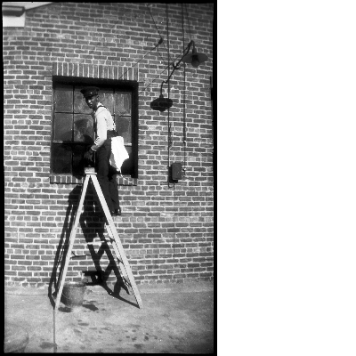 Man standing on ladder in front of brick building