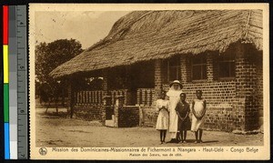 Missionary sister standing with three girls before a brick building, Congo, ca.1920-1940