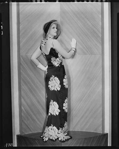 Peggy Hamilton modeling a black satin dinner dress with a floral design, 1931