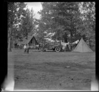 Distant view of Harry Schmitz, Donald Smith and Russell Smith standing in the campsite, Burney Falls, 1917