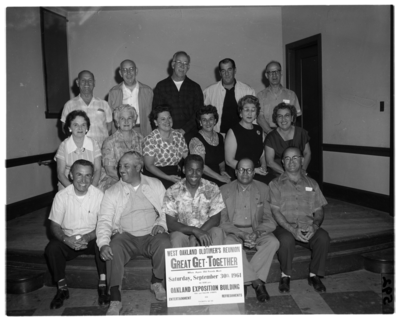 Group photograph of men and women in front of sign for West Oakland Oldtimers Reunion