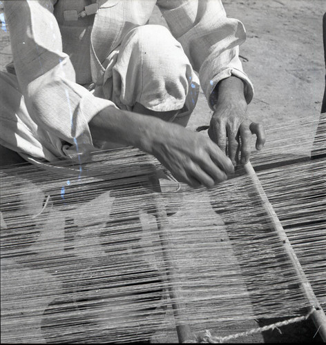 Close up of woman weaving at a street-side loom