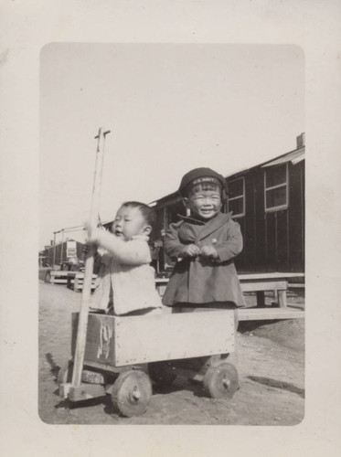 Two boys and a handmade wooden wagon at Poston incarceration camp