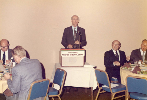 Speaker at the podium at LA World Trade Center, Dr. M. Norvel Young at table at Right (Color)