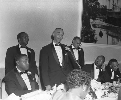 Man speaks at microphone at banquet table