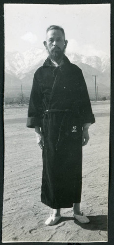 Photograph of a man in a robe standing with the Sierra Nevada in the background
