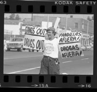 Guardian Angels member with bilingual signs reading "Gangs Out--Drugs Out" in Los Angeles, Calif., 1985