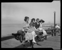 Four ladies seated on a pier railing, San Diego vicinity, 1920-1930