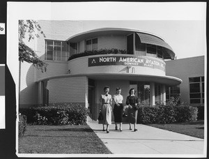 Three women walking by the exterior of the North American Aviation Downey airplane factory, September 1950