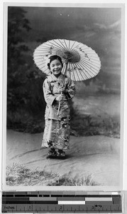 Portrait of a smiling Japanese girl holding an umbrella, Japan, ca. 1920-1940