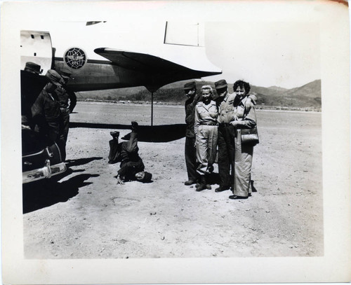 Military personnel posing next to plane