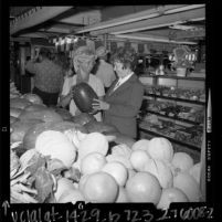 Two women inspecting melons at the Farmer's Market in Los Angeles, Calif., 1972