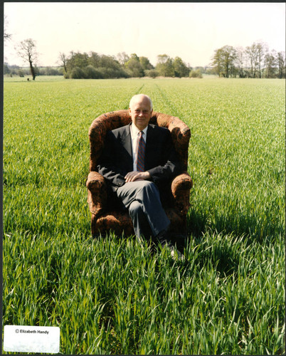 Charles Handy, color photo sitting in meadow