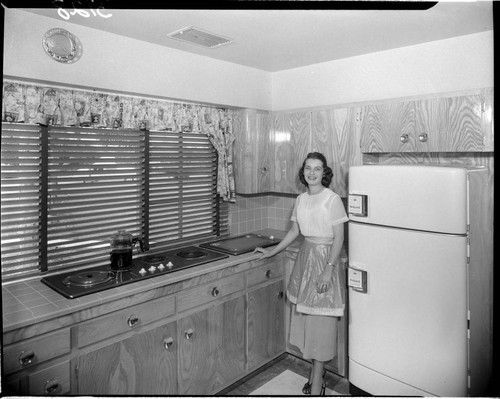 Lady standing in her kitchen by an electric range