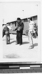 Father Lavery, MM, shaking hands with an internee at the Japanese Relocation Camp, Manzanar, California, ca. 1942