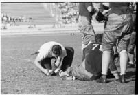Football player having his foot taped during a game between the Loyola Marymount Lions and St. Mary's Gaels at the Coliseum, Los Angeles, 1937