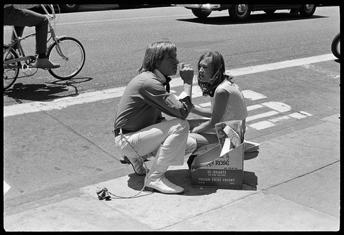 Couple sitting on sidewalk with bells on, Haight-Ashbury 1967
