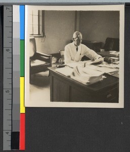 Dr. A. W. Tucker reading at his desk, Shanghai, China, ca.1925
