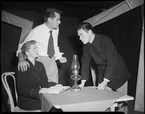 Two men and woman at small table, possibly acting in a play, [Santa Monica?], 1951