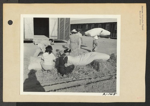 Poston, Ariz.--Evacuees of Japanese ancestry are filling straw ticks for mattresses upon arrival at this War Relocation Authority center. Photographer: Clark, Fred Poston, Arizona
