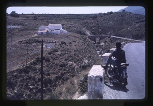 man on a motorcycle; likely a church in the distance