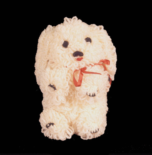 White crocheted dog with red ribbon tied around neck