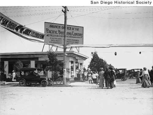 People and automobiles outside a branch office of the Pacific Building Company